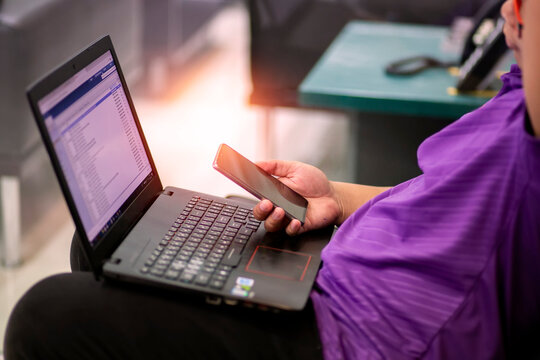 The Asian Man In A Purple Shirt Is Using A Laptop To Work. Asian Men Are Using Notebooks To Research Online.