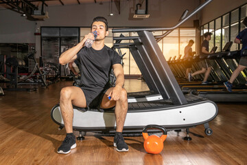 Fototapeta na wymiar Male fitness resting and drinks water after fitness workout in the gym
