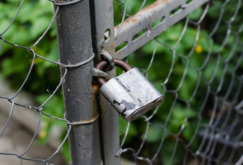 Metal padlock on the gate. Closed door. An old rusty padlock.