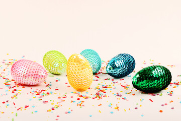 Colorful glossy easter eggs with sequins.Vivid pastry topping on the pastel background.Festive background.Free space for text.