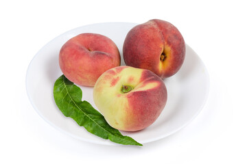 Various peaches and peach tree leaf on the white dish