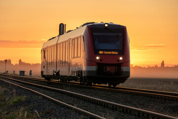 Fototapeta na wymiar Railcar driving through the countryside in a beautiful misty sunrise