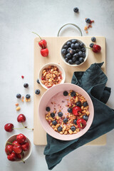Breakfast bowl with yogurt, blueberries, cherries and flakes on a grey table, flat lay style