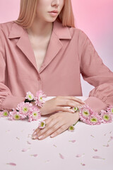 Beauty art portrait of a woman with pink flowers in her hands. Natural cosmetics for hands and face