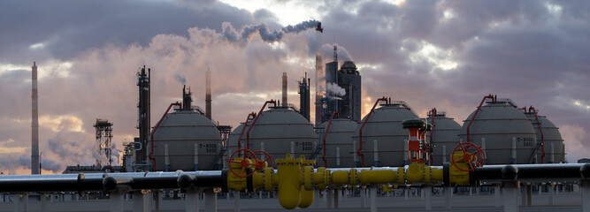 pipelines and fuel tanks in the fuel warehouse in the light of the setting sun against the...