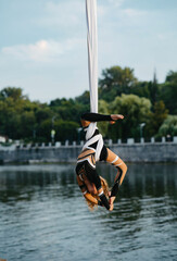 Child girl aerialist performs acrobatic tricks on hanging aerial silk .