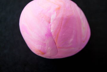 abstract background wavy shapes of pink color on a dark background from modeling dough.