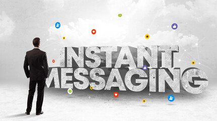 Young businessman standing in front of INSTANT MESSAGING inscription, social media concept