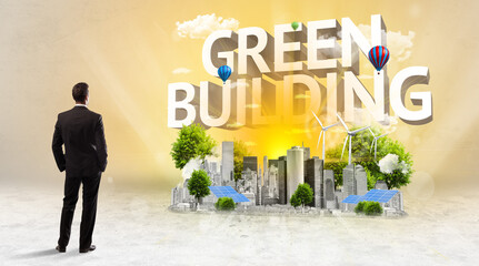 Fototapeta premium Rear view of a businessman standing in front of GREEN BUILDING inscription, Environmental protection concept