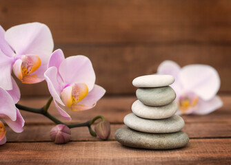 Fototapeta na wymiar Spa stones and a pink Orchid on a brown wooden background