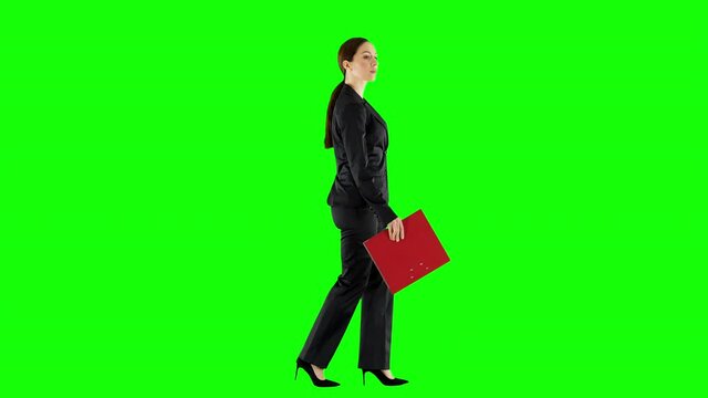 Businesswoman Carrying a Document Folder and Reading from It While Walking