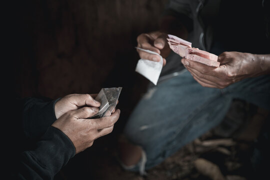 Dealer is holding drug bag and money in his hand on a black background. drug trafficking, crime, addiction and sale, copy space, The concept of buying and selling drugs.