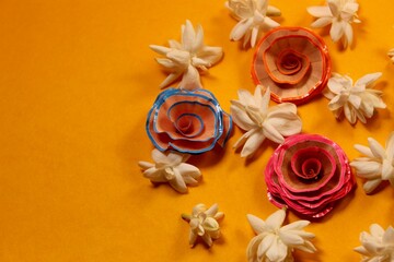 Fototapeta na wymiar Decorative background of rose shaped pencil shavings and white flowers on an orange background with copy space