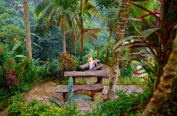 Woman in white dress sitting on the tropical porch near jungle villa.