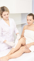 Fototapeta premium Hot hair removal depilation. Female skin routine. Sugar bodycare. Wax correction. Professional cosmetologist help girl. Sugaring bodycare cosmetics. Leg epilation. Vertical epilation process