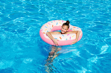 Cute smiling little girl in swimming pool with rubber ring