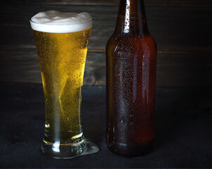 Mug of beer and bottle on table on wooden background