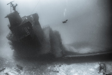Scuba diver underwater with shipwreck 