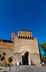 Fototapeta premium Nice portrait shot of the gate San Giovanni, the entrance of the walled medieval town San Gimignano in Tuscany, Italy. A church bell tower from a demolished church is still visible from the outside.