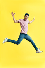 Happy excited man jumping on yellow background