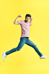 Fototapeta na wymiar Happy excited man jumping on yellow background