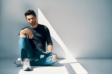 Young handsome man portrait sitting on floor in sun lights with copy space