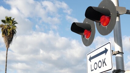 Level crossing warning signal in USA. Crossbuck notice and red traffic light on rail road...