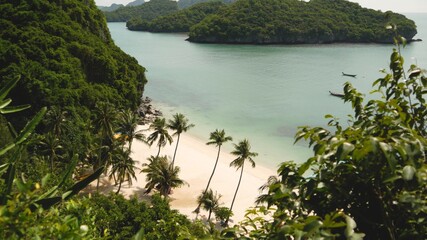 Calm sea near green jungle. Peaceful ocean with turquoise water, white sandy tropical shore in Ang Thong paradise national park, Thailand. Rainforest and rocks. Dream beach, relax and holiday concept