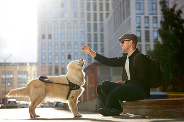 blind disabled man training golden retriever dog guide outdoors, giving obedience command