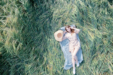 girl lies in a wheat field top view / summer vacation relaxation freedom, picnic in nature view from a copter