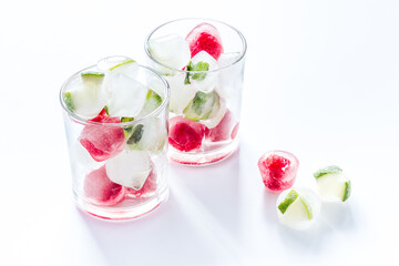 Cocktail glasses with berries in ice cubes on white table