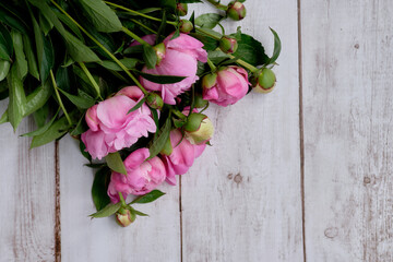 A bouquet of pink crimson peonies lie close-up on a wooden table