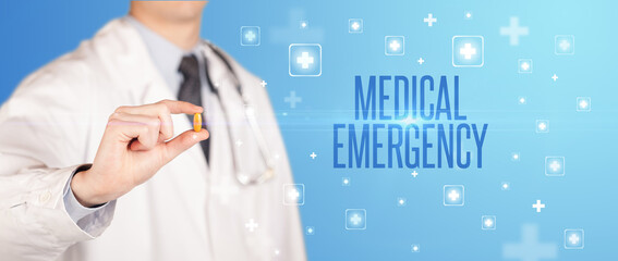 Close-up of a doctor giving a pill with MEDICAL EMERGENCY inscription, medical concept