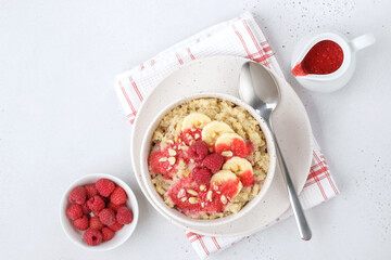 Quinoa porridge with banana, raspberry sauce and peanuts on white concrete background with copy spaceю Flat lay composition.
