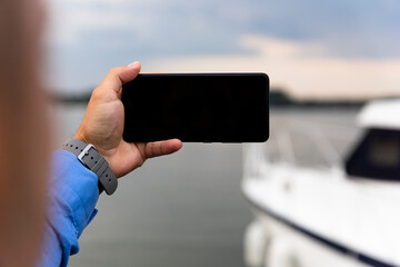 Man photographing Yacht with smartphone at the river