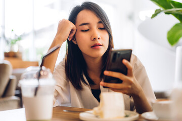 Portrait of smiling happy beautiful asian woman relaxing using digital smartphone.Young asian girl looking at screen typing message and playing game online or social media at cafe