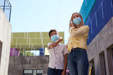 mother and child in medical masks in streets, they walk outdoors after quarantine ending. coronavirus outbreak