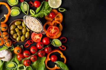 Background healthy food - raw tomatoes, peppers, olives, garlic on a black background, bright color, vitamin food with copy space