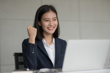 Young beautiful Asian business woman felling happy or success after look at notebook computer.
