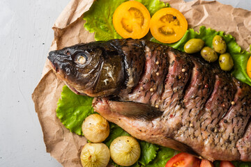 Baked stuffed fish carp with vegetables. on a gray background