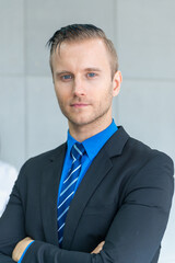 Portrait photo of handsome caucasian business man in formal suit uniform standing in office meeting room.