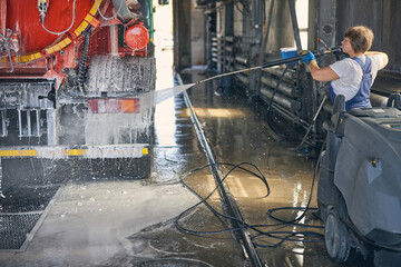 Attentive female person pouring down water on the car