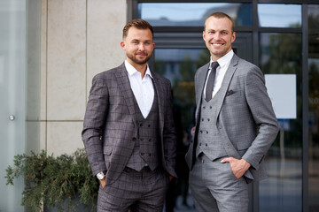 portrait of confident business partners outdoors, two caucasian men look at camera, wearing formal...