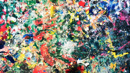 Colorful pour the paint texture on the surface of the wooden table. Splash acrylic multi color on old dirty wood table of children's artist table. Close up abstract background. 