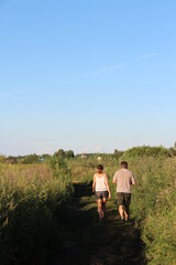 Couple walking down a field road in summer