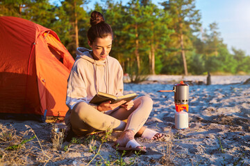 Beautiful female traveler reading book on the beach