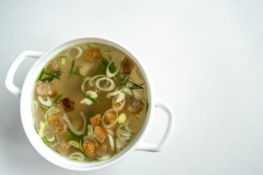 Homemade meat broth in a tureen with dill, onions and croutons. on a white background. Healthy food concept. Top view.