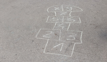 Jumping hopscotch game with numbers outdoors on a sunny day. Summer activities for children