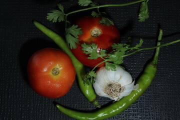 Green chilly, Garlic, Tomato, Onion and Curry leaf are isolated on black background. Ingredients concept. Hot and spicy green chillies and fresh ripe tomato, Onion on black background.