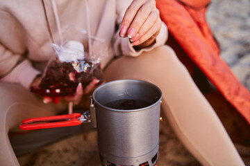 Female traveler making hot drink during camping
